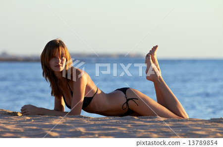 Young woman in bikini posing on sea coast Young woman in bikini posing on sea coast 13789854