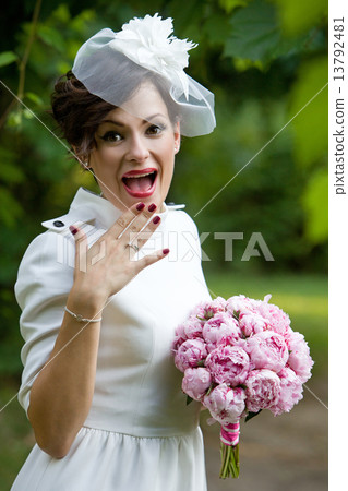 Happy bride laughing, covering mouth with her hand with bouquet of peony flowers. 13792481