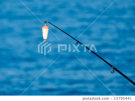 Fishing Bait-Rod with Float against the Blue Sea Water Surface 13795441