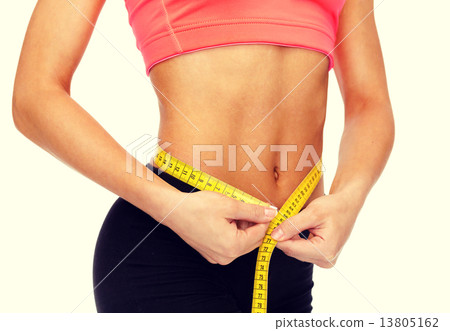close up of female hands measuring waist 13805162