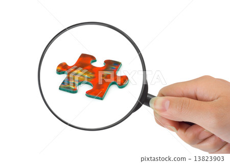 Hand with magnifying glass and puzzle 13823903