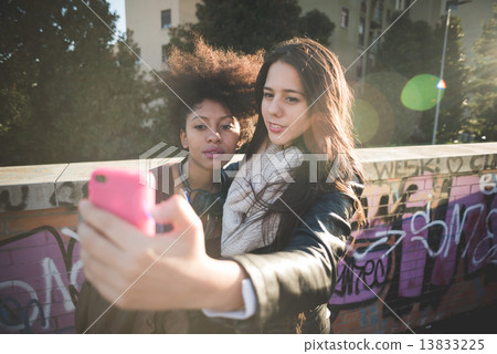 two multiethnic beautiful young woman black and caucasian having 13833225