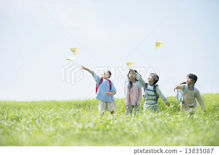 Elementary school student who flies paper airplane in the grassland 13835087