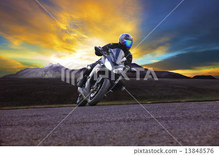 young man riding motorcycle in asphalt road curve with rural and 13848576