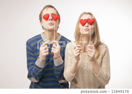 Couple hiding their eyes behind little red hearts Couple hiding their eyes behind little red hearts 13849178