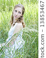 Photo of young blonde woman sitting in the green grass and looki 13853467
