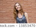 Photo of blonde girl with bright sincere smile on red brick back 13853470