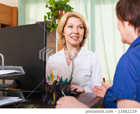 Mature doctor consulting female patient Mature doctor consulting female patient 13862229