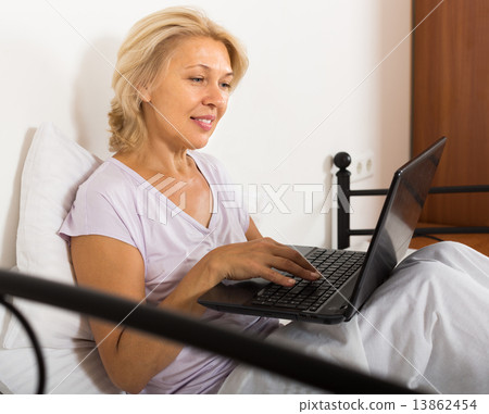 Mature woman with laptop in bed 13862454