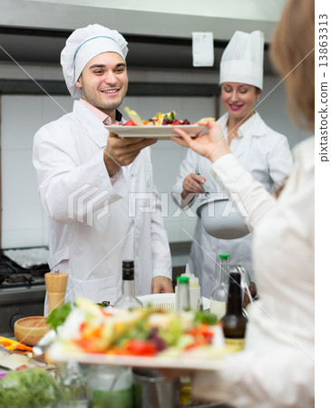 Female waiter taking dish at kitchen Female waiter taking dish at kitchen 13863313