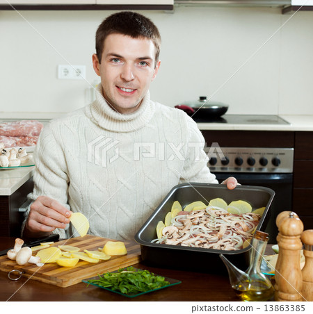 Guy cooking meat in roasting pan 13863385