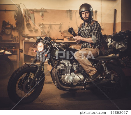 Rider and his vintage style cafe-racer motorcycle in customs garage 13868037