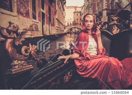 Beautiful woman in red cloak riding on gondola Beautiful woman in red cloak riding on gondola 13868084