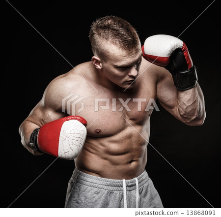 Muscular young man wearing boxing gloves Muscular young man wearing boxing gloves 13868091