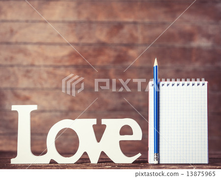 Pencil and notebook with word Love on wooden background. 13875965