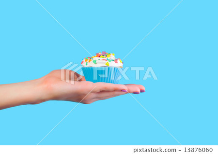Hand holding cupcake on blue background Hand holding cupcake on blue background 13876060