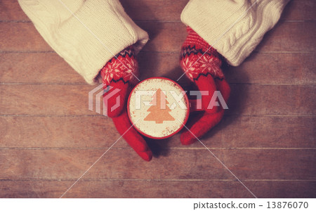 Hands in mittens holding hot cup of coffee Hands in mittens holding hot cup of coffee 13876070