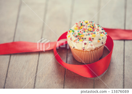 Cupcake and bow on wooden table. Cupcake and bow on wooden table. 13876089