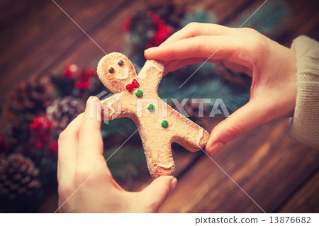 Female holding gingerbread man near pine branches. 13876682
