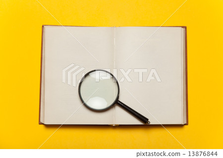 Opened book and loupe on color background. 13876844