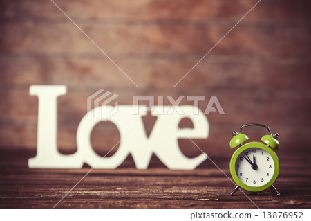 Clock with word love on wooden table. 13876952