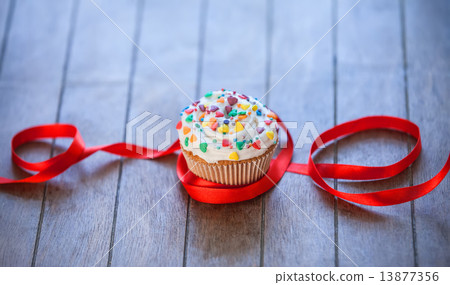 Cupcake and bow on wooden table. Cupcake and bow on wooden table. 13877356