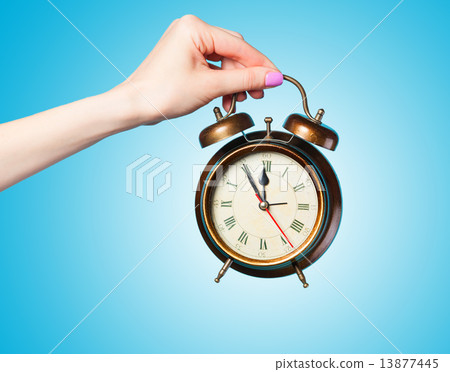Hand holding alarm clock on blue background. Hand holding alarm clock on blue background. 13877445