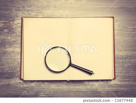Book and loupe on wooden table. Book and loupe on wooden table. 13877448