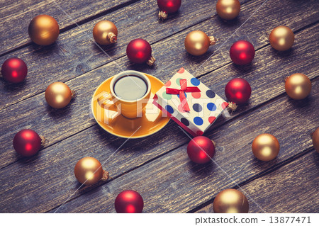 Cup of coffee and christmas balls and gift on wooden table. 13877471