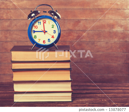 Alarm clock and books on wooden table. 13878077