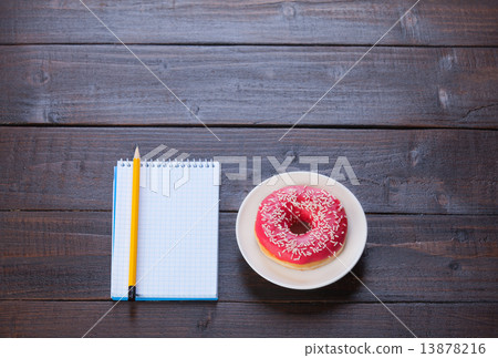 Notebook, donut and pencil on wooden table. Notebook, donut and pencil on wooden table. 13878216