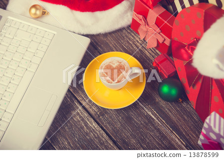 Cup of coffee with heart shape, laptop and christmas gifts. Cup of coffee with heart shape, laptop and christmas gifts. 13878599