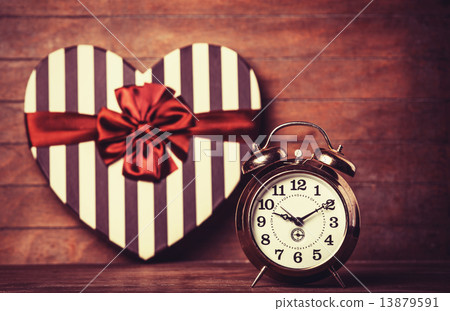 Retro clock and gift in heart shape on the background. Retro clock and gift in heart shape on the background. 13879591