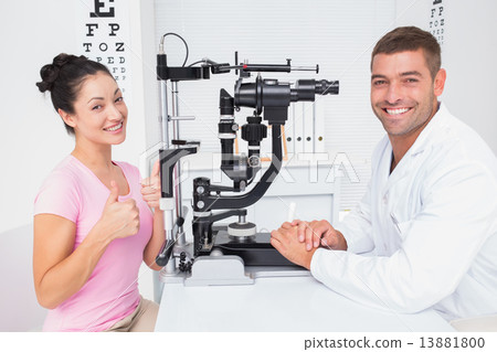 Patient gesturing thumbs up while sitting with optician 13881800