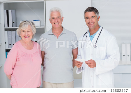 Happy senior couple with doctor standing in clinic 13882337