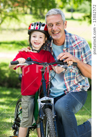 Happy little boy on his bike with his father 13882572