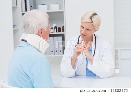 Doctor looking at senior patient wearing neck brace 13882573