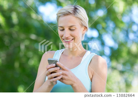 Pretty blonde using smartphone 13882664