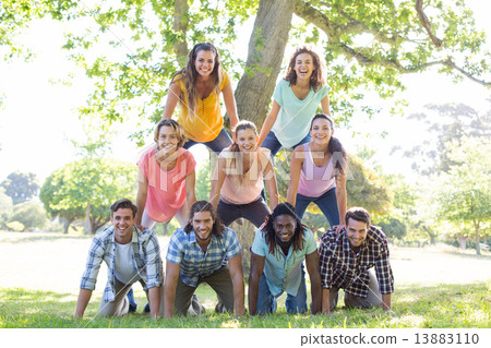 Happy friends in the park making human pyramid Happy friends in the park making human pyramid 13883110