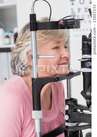 Senior patient looking into slit lamp 13883333