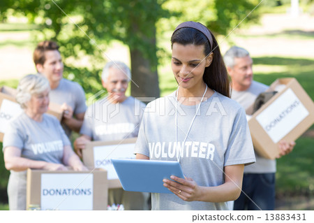 Smiling volunteer brunette using tablet pc Smiling volunteer brunette using tablet pc 13883431