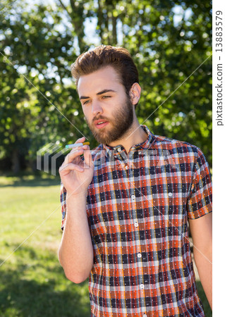 Hipster smoking an electronic cigarette Hipster smoking an electronic cigarette 13883579