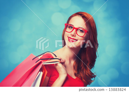 Redhead girl with shopping bags on blue background. 13883824