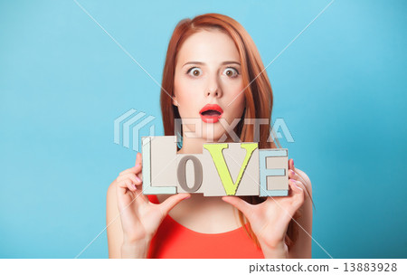 Surprised redhead women with word Love on blue background. 13883928