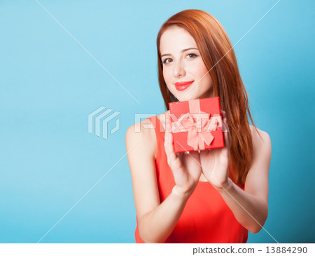 Smiling redhead women with gift on blue background. Smiling redhead women with gift on blue background. 13884290