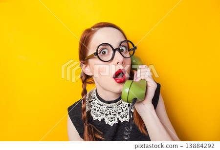 Redhead girl with green phone on yellow background. Redhead girl with green phone on yellow background. 13884292