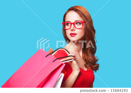 Redhead girl with shopping bags on blue background. Redhead girl with shopping bags on blue background. 13884293