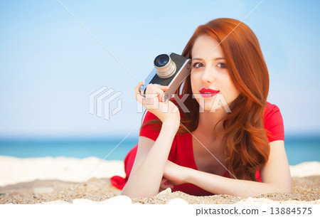 Redhead girl with camera on the beach Redhead girl with camera on the beach 13884575