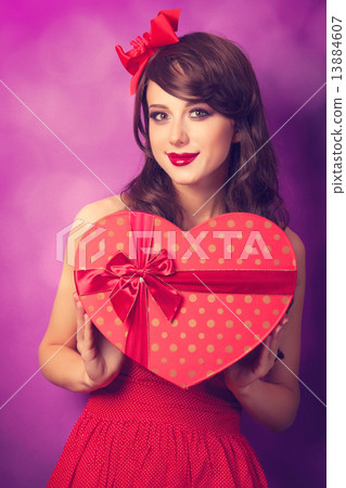 Beautiful brunette girl with heart shape gift on violet backgrou 13884607