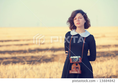 Beautiful brunette girl with camera on the countryside field 13884842